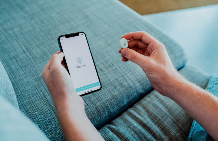 Person holding up the NightOwl home sleep test device next to phone 