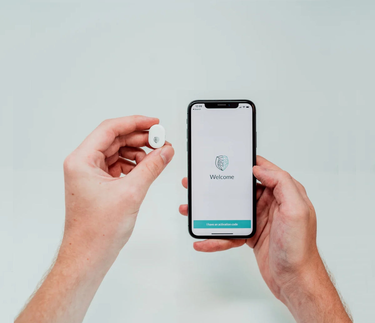 Person holding the NightOwl home sleep test device next to phone displaying the NightOwl Companion app
